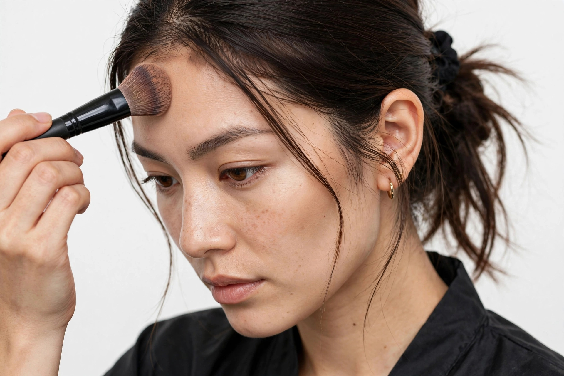 Woman contouring her forehead and chin with makeup brush
