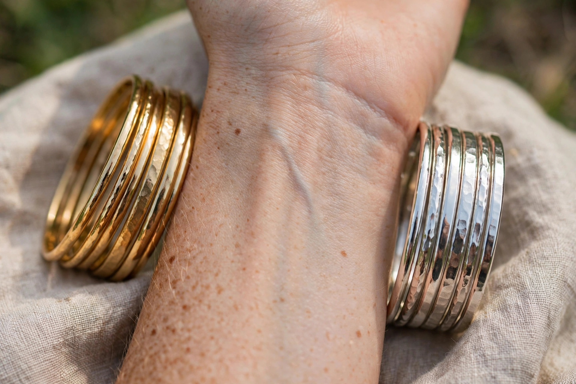 Close-up of a wrist in daylight with gold and silver bracelets compared against the skin